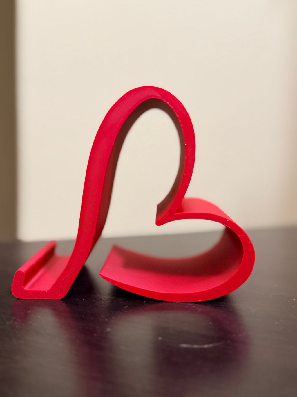 Heart phone stand holding a smartphone, side view