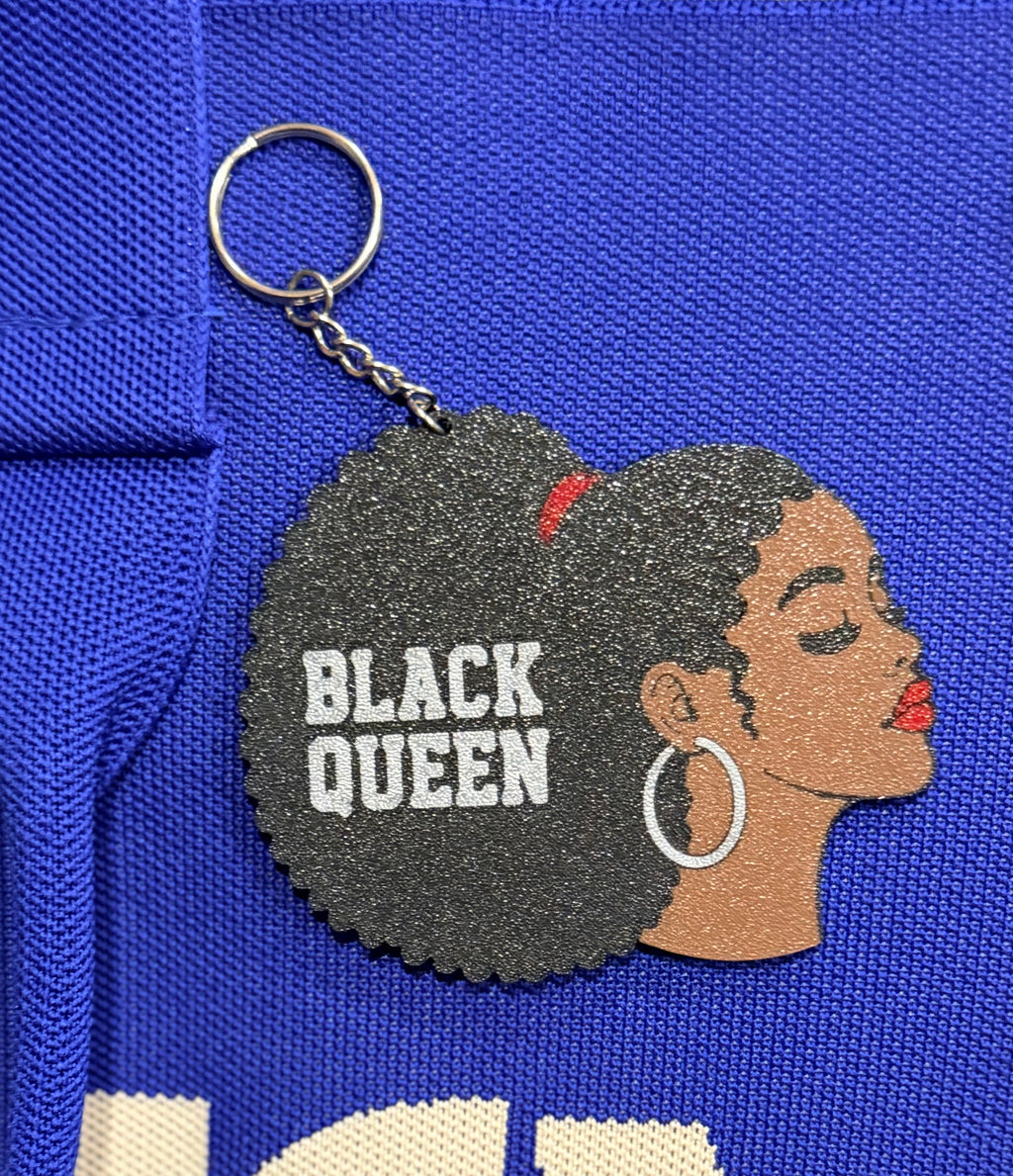 Black Queen keychain clipped to blue fabric