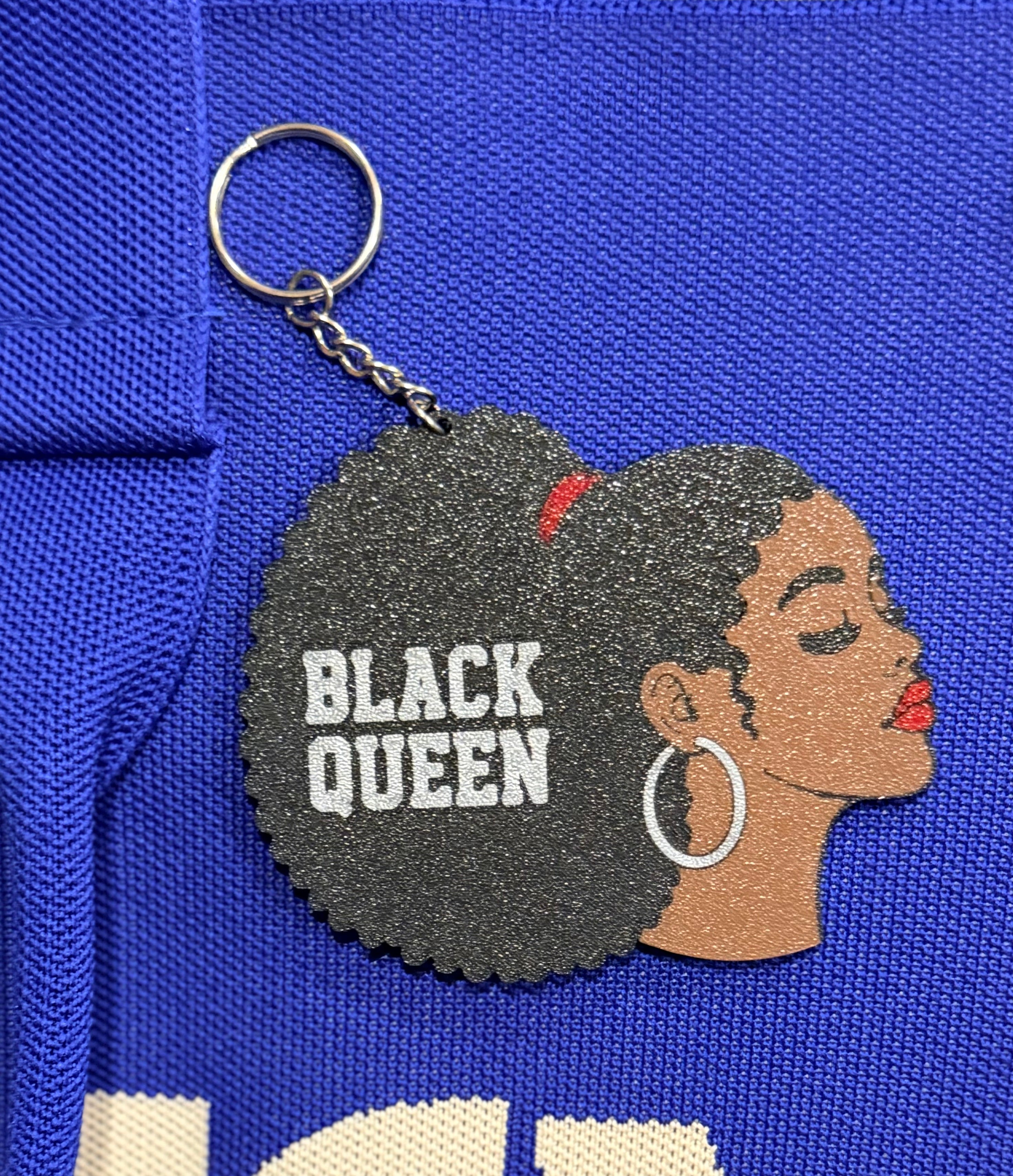 Black Queen keychain clipped to blue fabric