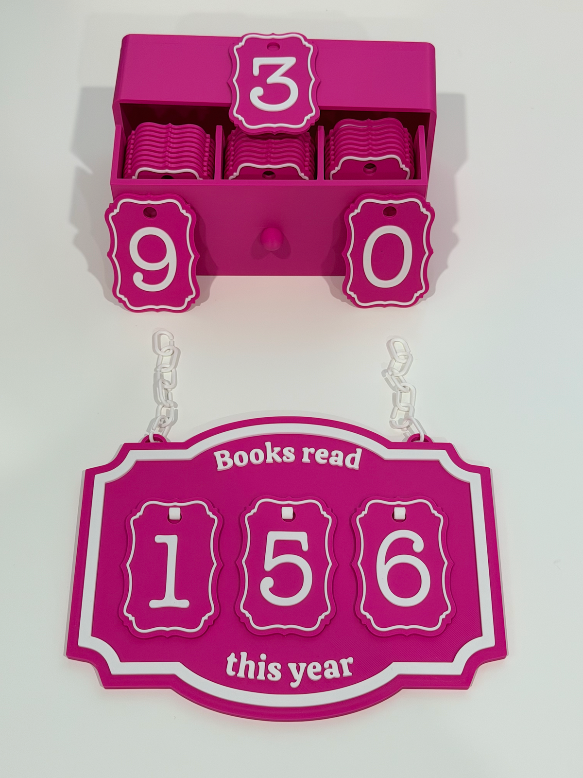 3D-printed Books Read This Year reading tracker set in hot pink and white, showing hanging sign with number tiles and matching storage box